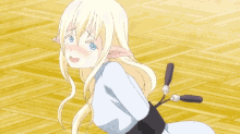 a blonde anime girl with blue eyes is sitting on the floor