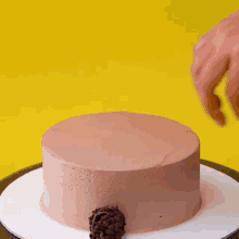 a cake with a pink frosting is surrounded by chocolate balls on a yellow background