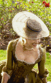 a woman wearing a hat and a pearl necklace smiles