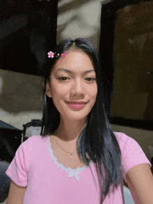 a girl wearing a pink shirt with flowers on her hair
