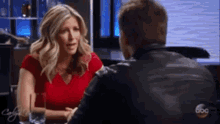 a man and a woman are sitting at a table and talking to each other .