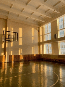 an empty gym with a basketball hoop and a few windows