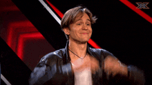 a man in a leather jacket is clapping his hands in front of a red and white background with a x on it
