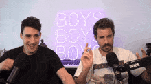 two men standing in front of a sign that says boys boys boys