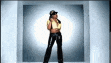 a woman in a yellow shirt and black pants is standing in front of a white wall