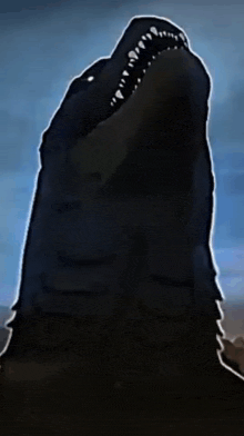 a silhouette of a monster with its mouth open against a blue sky
