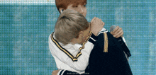 a couple of young men hugging each other while one of them is holding a microphone .