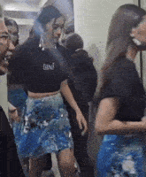 a woman wearing a gini crop top and a blue sequined skirt