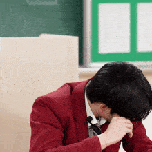 a man in a red suit and tie is covering his face