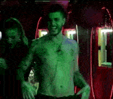 a man without a shirt is dancing in a dark room while a woman looks on .
