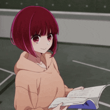 a girl with red hair is holding a book that says ' a ' on it