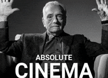a man is sitting in a chair with his hands in the air and absolute cinema is written below him