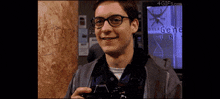 a man wearing glasses is holding a camera in front of a screen that says gene