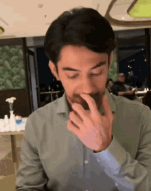 a man covering his mouth with his hand in a restaurant