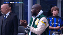 a man wearing a digitalbits jersey applauds during a soccer match