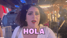 a woman wearing a white shirt says hola in pink letters