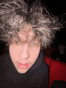 a young man with a black hoodie has a messy hairdo