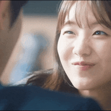 a close up of a woman 's face with a man in the background