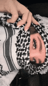 a woman wearing a black and white scarf covers her face