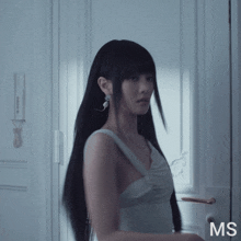 a woman in a white dress is standing in front of a white door with the letters ms on it