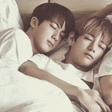 two young men are sleeping next to each other on a bed with their eyes closed