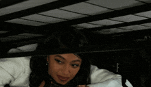 a woman is laying underneath a bed with a bag that says godiva