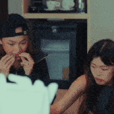 a woman wearing a baseball cap is eating a piece of food