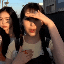 a girl covering her face with her hand while another girl looks at her