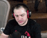 a man wearing headphones is sitting in front of a microphone and looking at the camera .