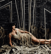 a woman is laying on a pile of ropes with the letters ff and ar visible on the wall behind her