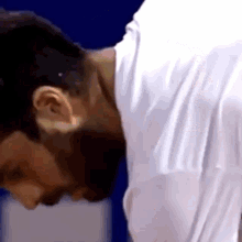 a man in a white shirt is bending over and looking down