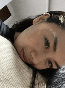 a woman with a ring in her ear is laying down with her head on a pillow