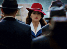 a woman in a red hat is standing in a crowd of men