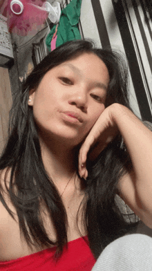 a woman in a red top is taking a selfie with her hand on her face