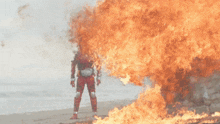 a man in a red suit is standing in front of a fire