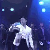 a man in a white suit and bow tie is holding a bucket in his right hand