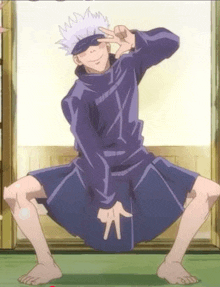 a man in a purple shirt is squatting down with his legs crossed and making a peace sign .