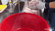 a person is washing a piece of meat in a red strainer
