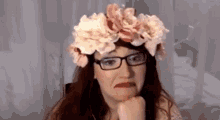 a woman wearing glasses and a flower crown on her head .