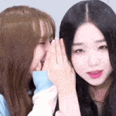 two women are whispering into each other 's ears .
