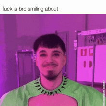 a man wearing a green shirt with spikes around his neck is smiling in front of a purple background ..