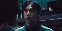 a man in a green jacket looks at another person
