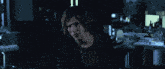a man with red hair is sitting at a table in a dark room looking at a computer screen