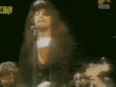 a blurry picture of a man singing into a microphone in front of a sign that says ' es ' on it