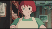 a woman with red hair is wearing a green apron and smiling