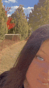 a close up of a girl 's face with a blurred background of trees