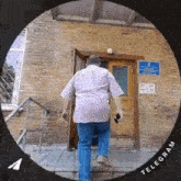 a man in a pink shirt and blue jeans is walking down stairs in front of a brick building .