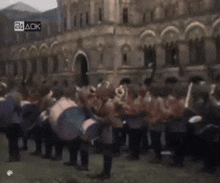 a group of people playing drums in front of a building that says 24 ack on the bottom