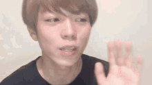 a close up of a young man 's face with his hand out .