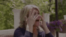 a woman is covering her face with her hands while sitting on a couch .
